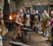 Participants observe a blacksmith demonstrating techniques at a workshop, highlighting Blacksmithing Workshops & Events 2026-27.